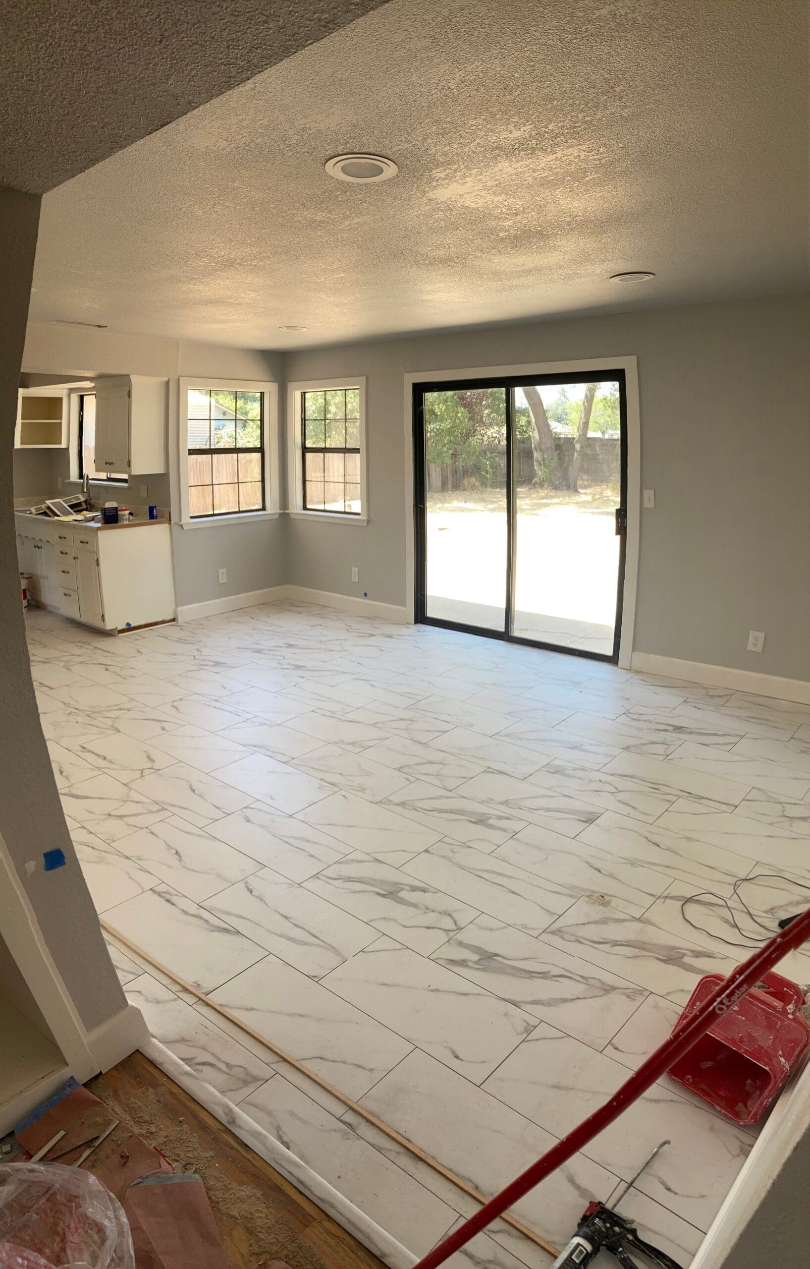 Dining room remodel featuring marble-look tile flooring, gray walls, white trim, and sliding glass patio door by On Point Construction.