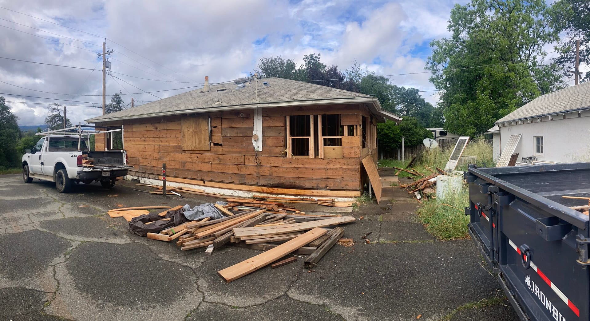 Exterior dry rot and termite damage repair showing stucco removal, exposed wood sheathing, and window framing during residential restoration.