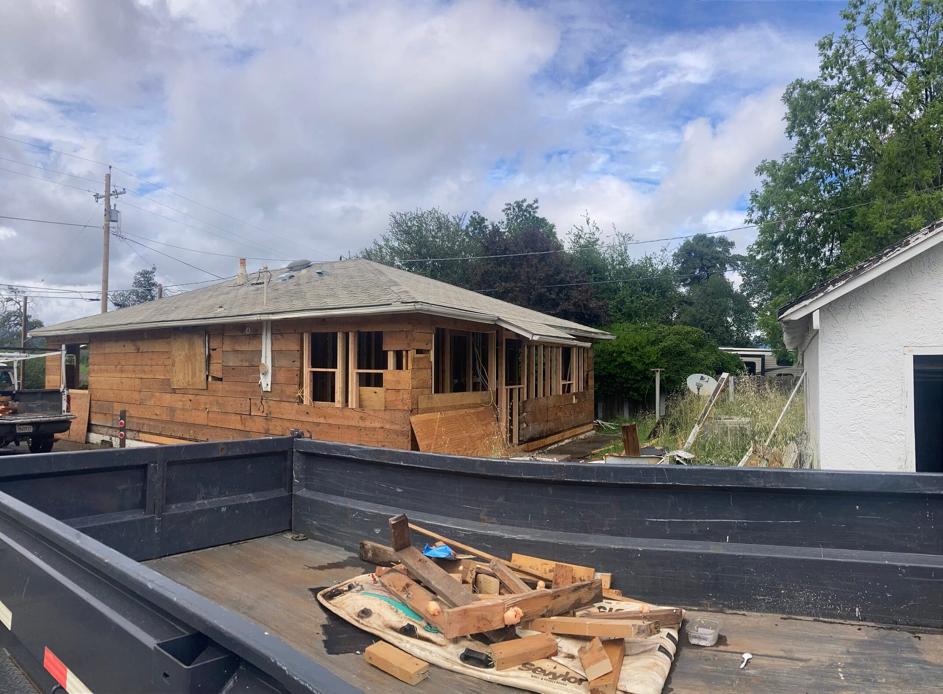 Exterior dry rot and termite damage repair showing stucco removal, exposed wood sheathing and window openings during home restoration by On Point Construction.