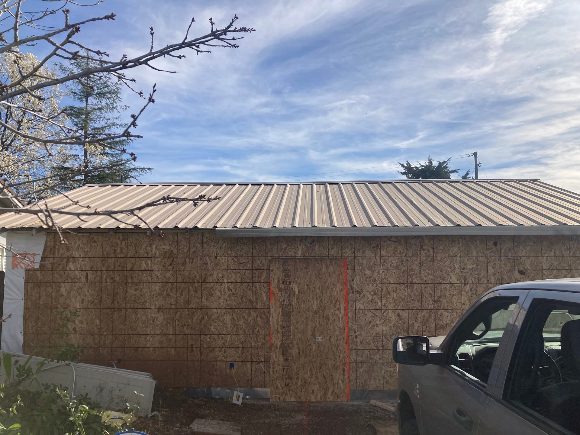 Metal roof replacement project showing exterior wall sheathing and newly installed metal roofing during reroof work by On Point Construction.