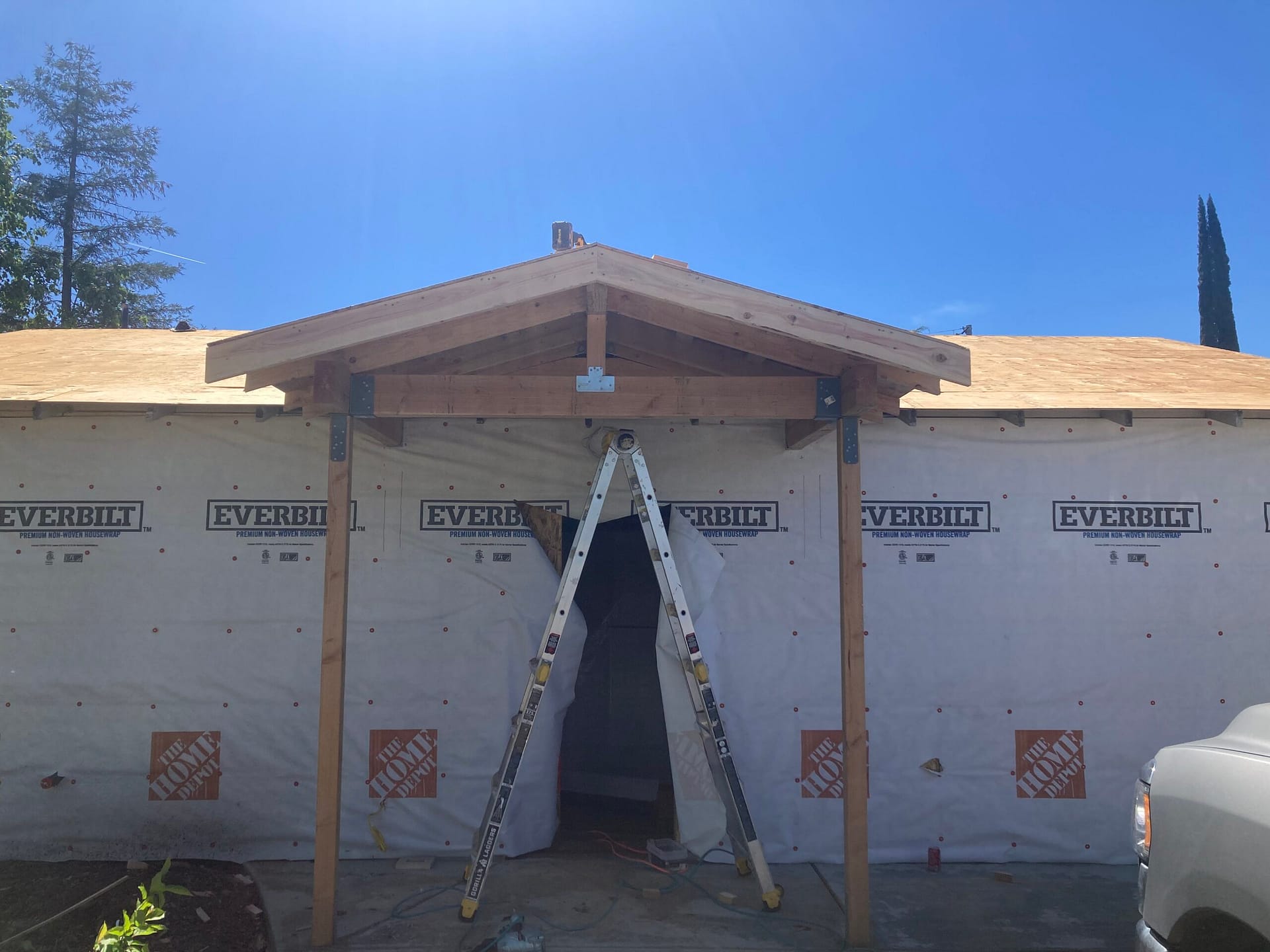 New covered front porch construction with wood gable roof framing, support posts, and new roof sheathing during residential reroofing by On Point Construction.