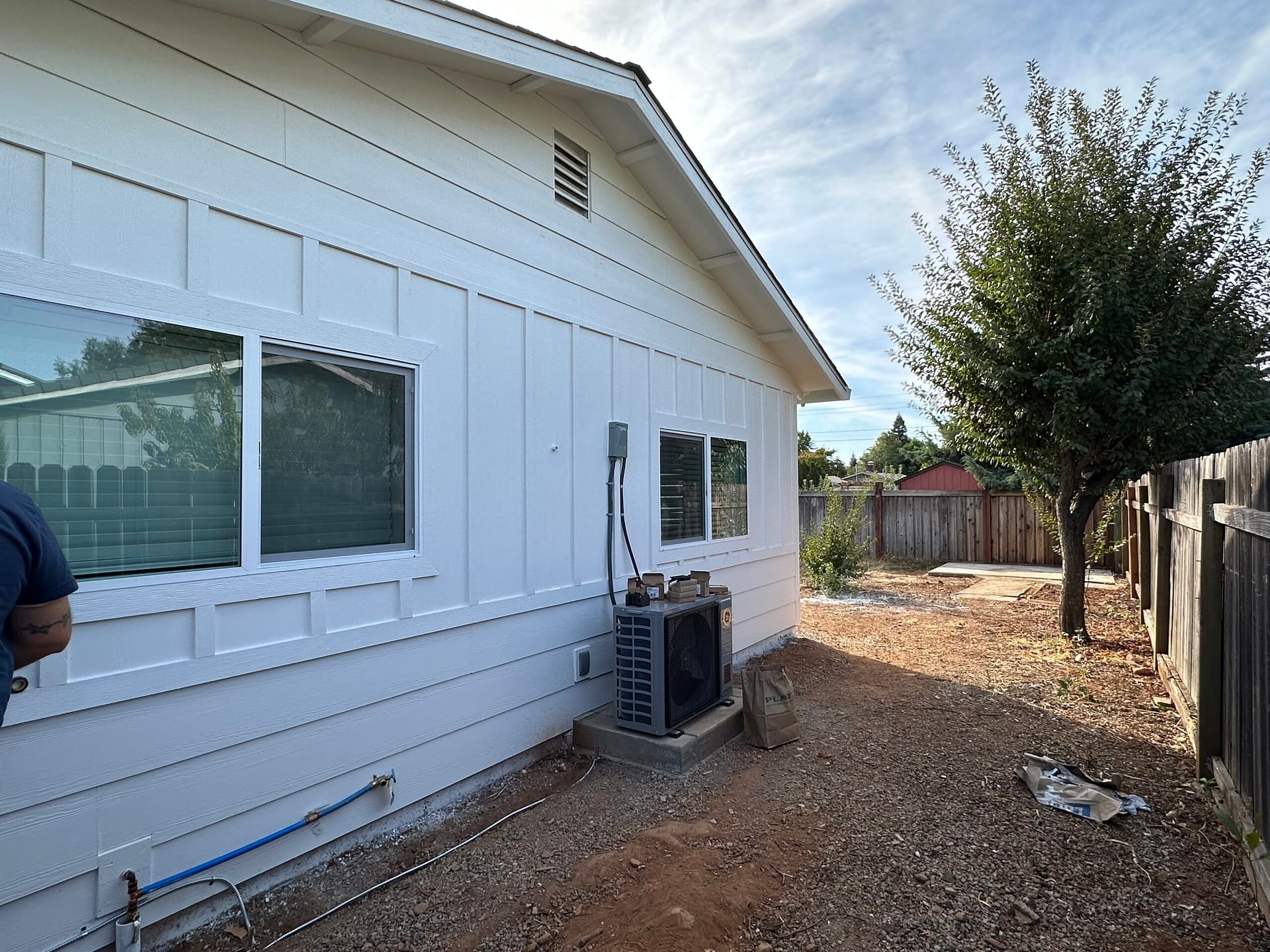 Mini-split outdoor condenser installed beside a converted garage ADU in Redding, CA, with white board-and-batten siding and new windows.