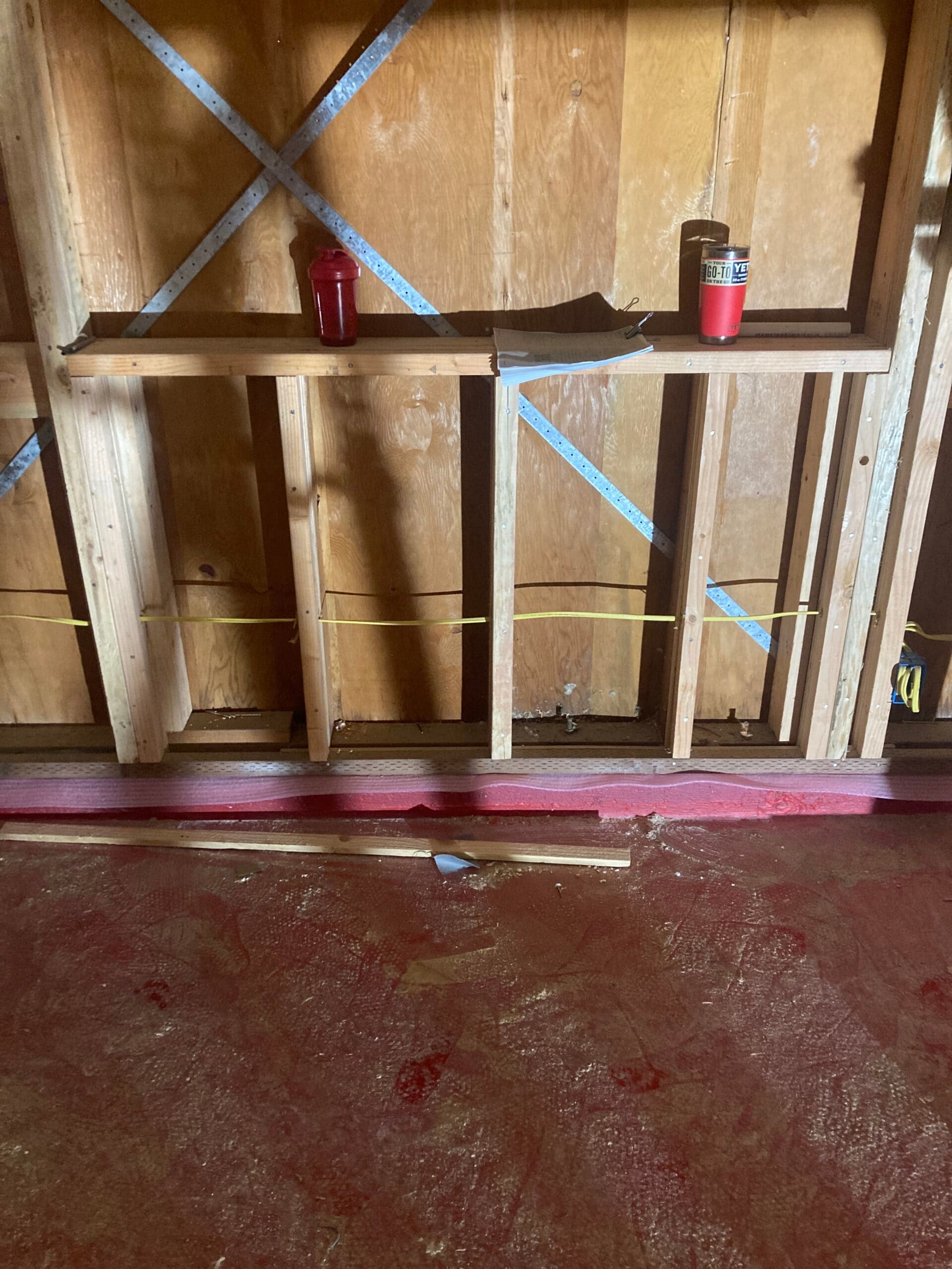 Residential window framing during home remodeling, showing exposed wood studs, horizontal framing, and metal wall bracing by On Point Construction.