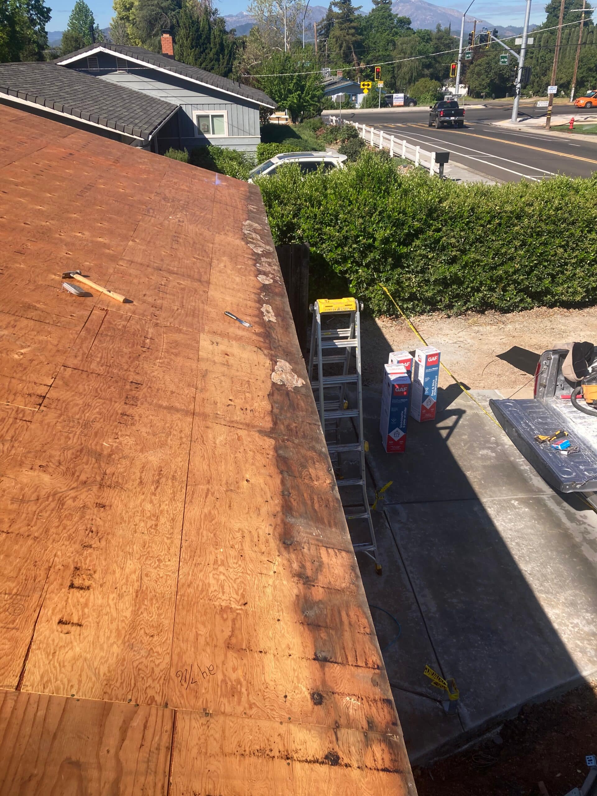 Residential roof damage repair showing exposed plywood roof decking during roof restoration by On Point Construction.