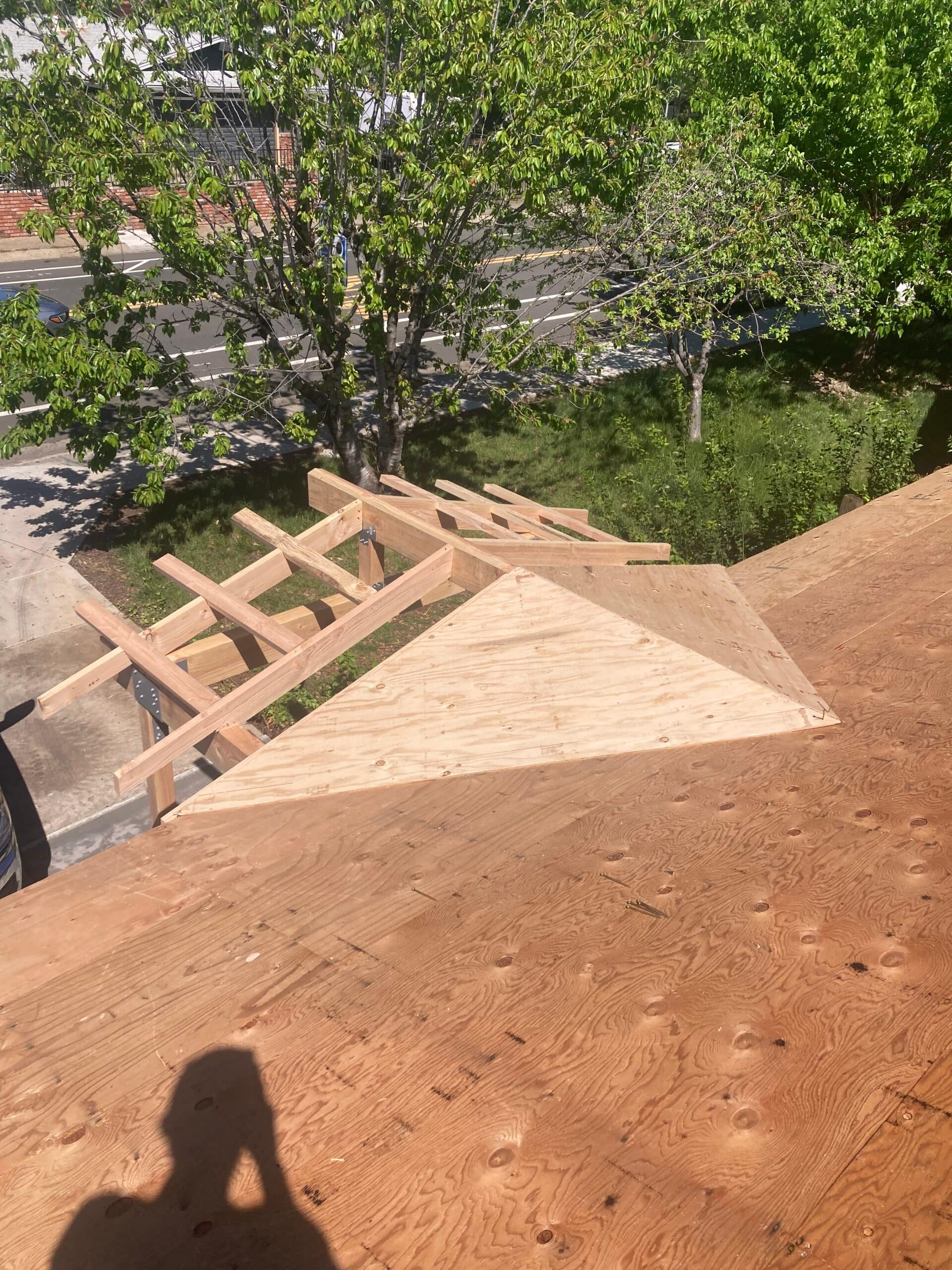 New covered porch framing and roof sheathing during reroof construction by On Point Construction.