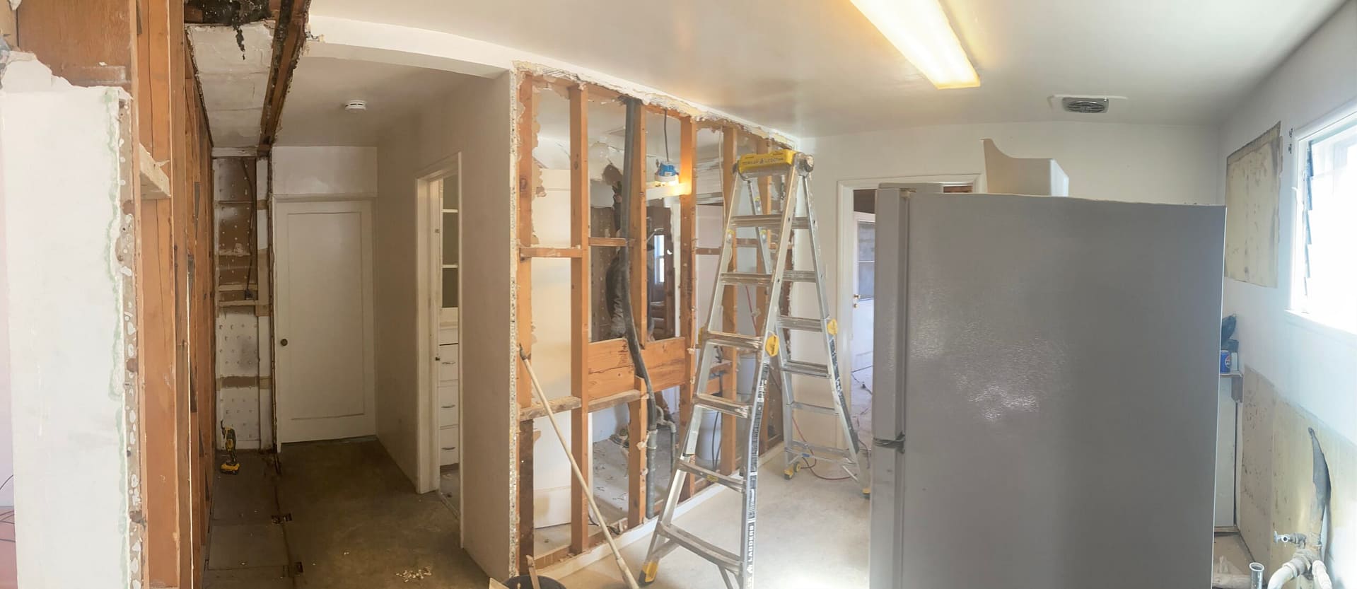 Interior demolition during kitchen remodeling showing removed drywall, exposed wall studs, and opened interior walls by On Point Construction.