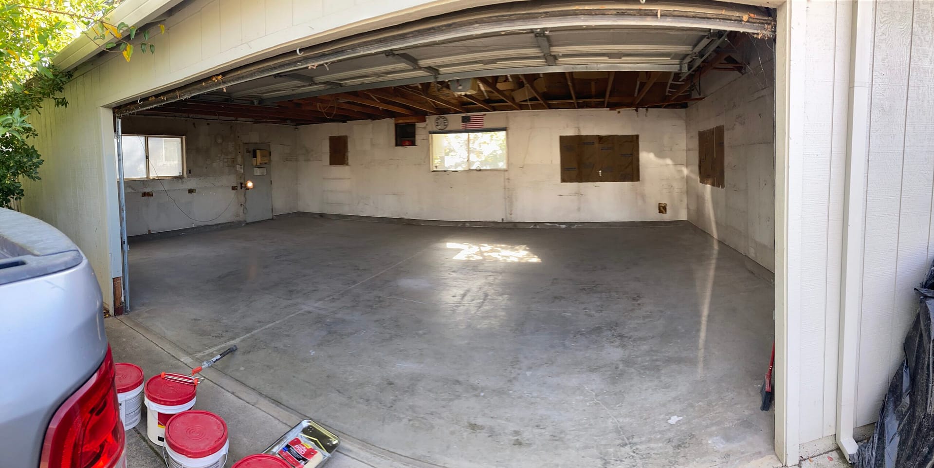 Garage to ADU conversion in progress with cleared concrete floor, exposed ceiling framing, and interior demolition by On Point Construction.