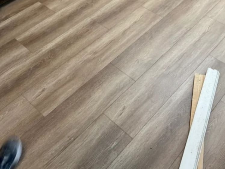 Flooring installation in progress with wood-look planks being laid