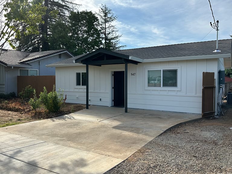 Garage conversion into an ADU in Redding, with white siding, replacement windows and a covered entry built by On Point Construction.