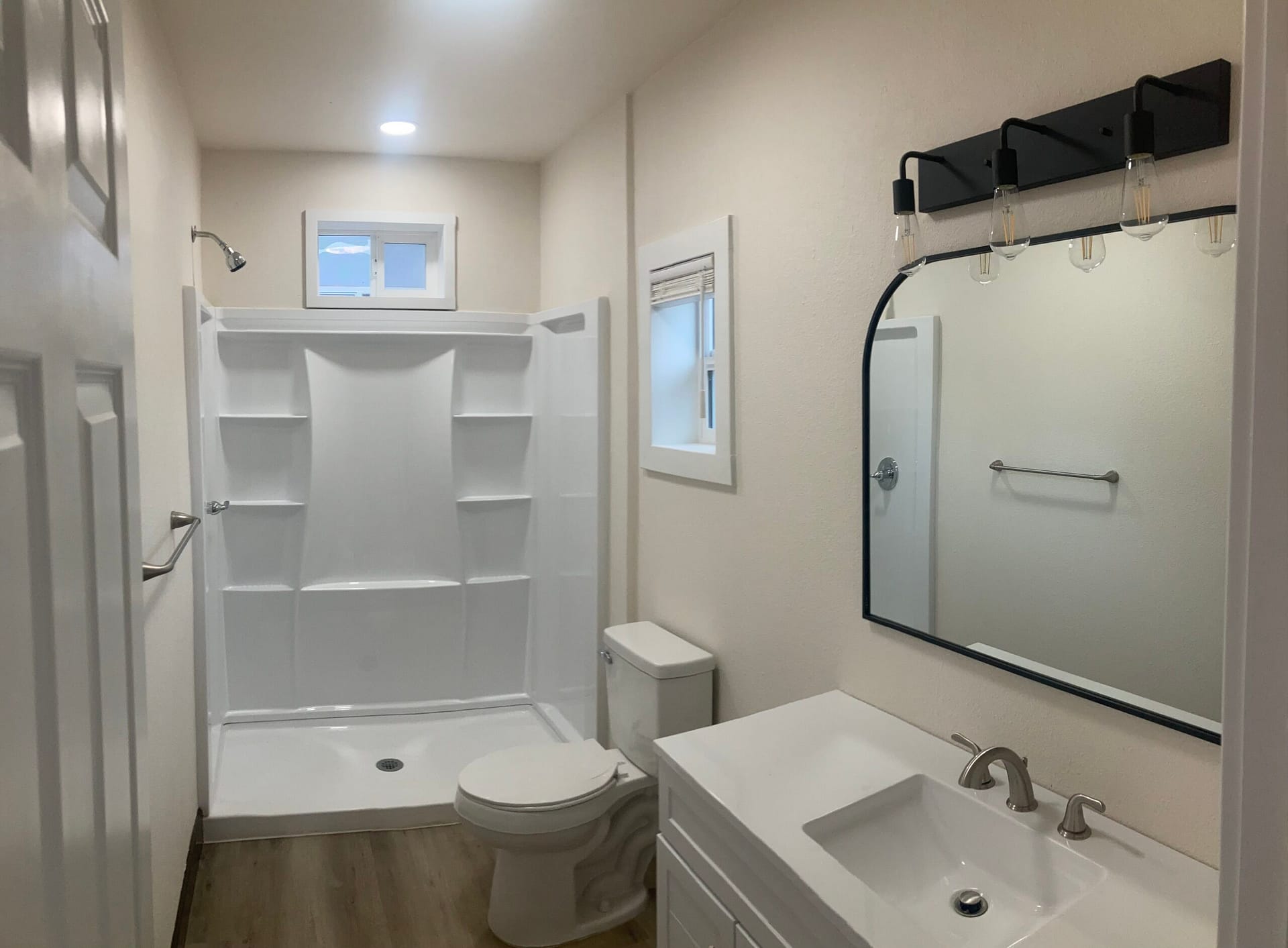 Completed bathroom in On Point Construction's Redding garage-to-ADU conversion, with a walk-in shower, white vanity and modern fixtures.